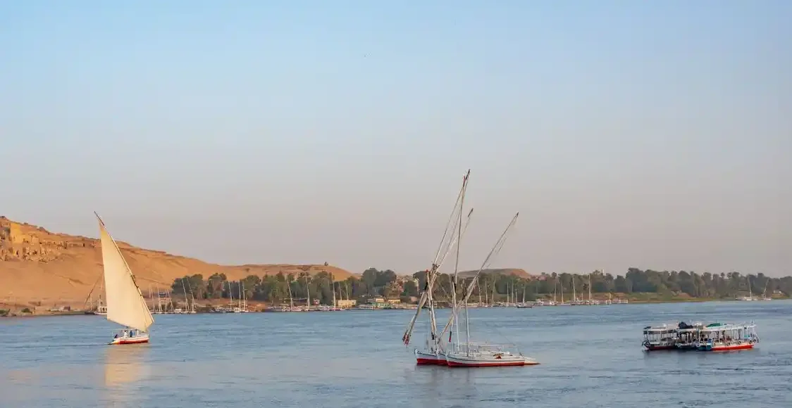 A luxury Nile cruise sailing between Luxor and Aswan during a golden sunset, organized by The Holiday Escape.