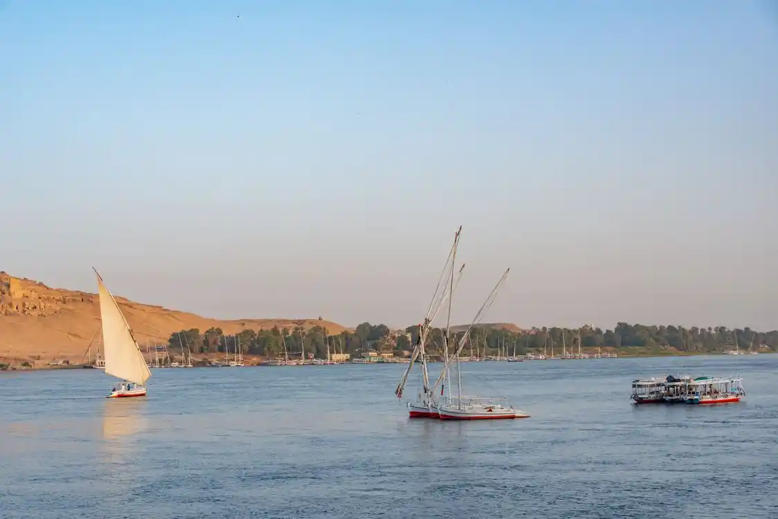 A luxury Nile cruise sailing between Luxor and Aswan during a golden sunset, organized by The Holiday Escape.
